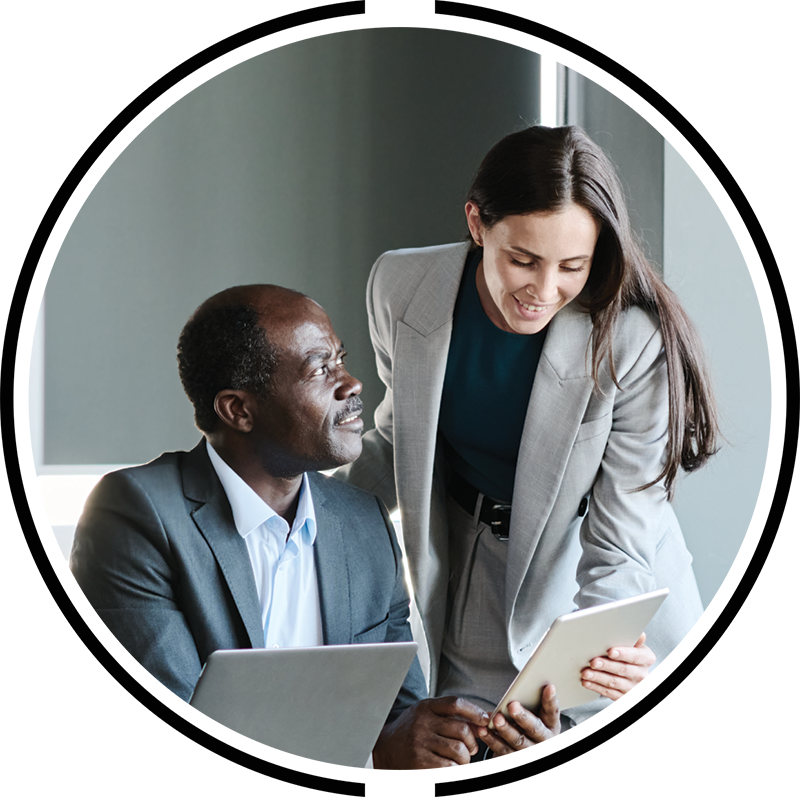A man and a woman in a corporate office smiling and discussing a documeny they are holding