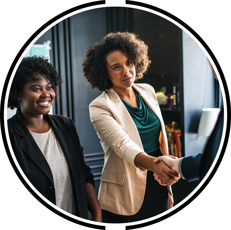 Two professional women shaking the hands of man in an office setting